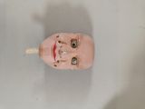 a pink doll head with a toothpick sticking out of it