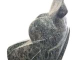 statue of a woman sitting on a rock with a bird on her back
