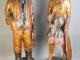 deux statues en bois représentant un homme et une femme debout l'un à côté de l'autre