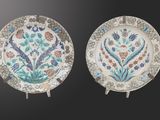 two plates with floral designs on them on a black background