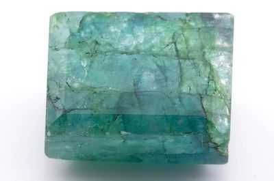 un gros plan d'une pierre verte sur une surface blanche