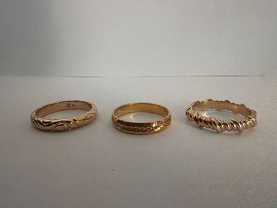 three different types of gold rings on a white surface