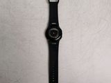 the watch is sitting on a white surface with a black strap
