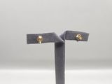 a pair of gold stud earrings on a stand