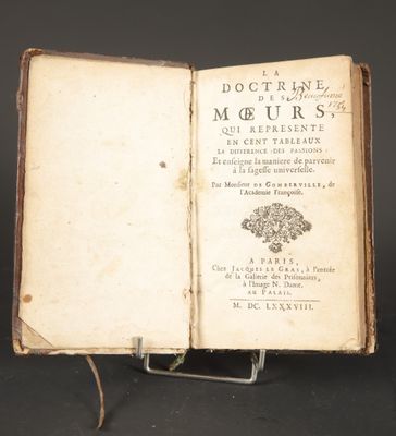 an open book sitting on top of a metal stand on a black surface