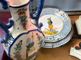 un vase bleu et blanc posé sur une table, à côté d'une pile d'assiettes