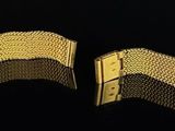 two pieces of gold colored metal on a black surface