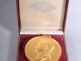 l'image d'une médaille d'or dans un coffret rouge posé sur un fond blanc