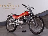 a red motorcycle parked in front of the pinnacle collection sign