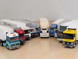 Plusieurs camions miniatures sont alignés sur une table en bois