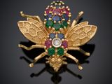 un gros plan d'une broche en forme d'abeille en or, ornée de pierres multicolores