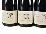 four bottles of wine are lined up on a white surface