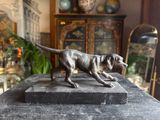 statue of a dog running on a marble block in a living room