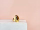 un gros plan d'une bague en or posée sur un bloc de marbre