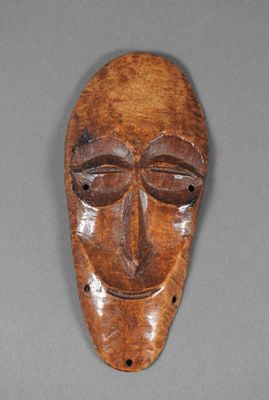 un vieux masque en bois posé sur une surface grise