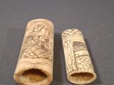 pair of carved ivory toothpicks with figures on them on a gray surface