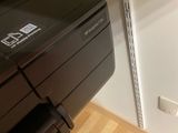 a black printer sitting on a shelf next to a white wall