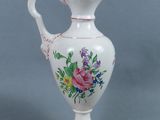 un vase blanc avec une anse rose et des fleurs peintes dessus