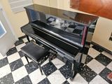 a black piano sitting in a room with a checkered floor