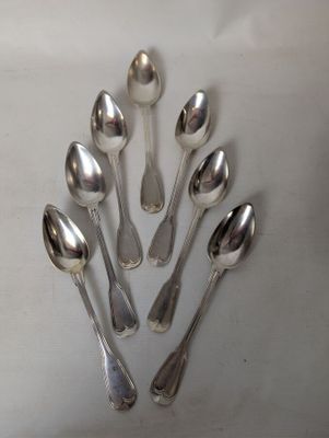 six silver spoons are arranged in a circle on a white surface