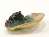 a figurine of a frog in a shell on a white surface