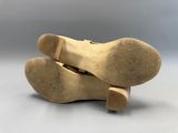 une paire de chaussures en cuir beige posées l'une sur l'autre sur une surface blanche