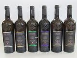 six bottles of wine are lined up in a row on a white surface