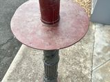 a red table with a cup on it on the sidewalk