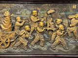 bronze relief of a group of people with a wagon