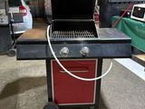une photo d'un barbecue dans un garage, avec une voiture en arrière-plan