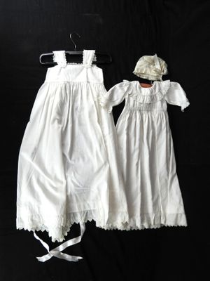 deux robes blanches et un chapeau sont représentés sur un fond noir