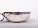 a silver bowl with a metal handle on a white surface