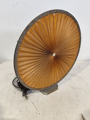 un grand ventilateur en bois posé sur une surface blanche