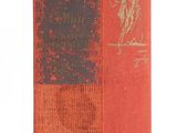 an old book with a red cover sitting on top of a white surface