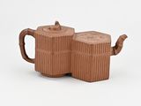 two brown ceramic teapots sitting on top of each other
