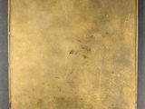 an antique brass plate with a label on it on a black surface