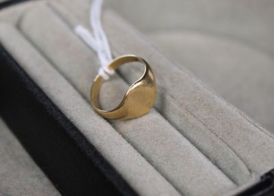 une bague en or posée dans une boîte, attachée à un cordon blanc
