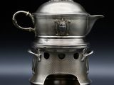 une théière ancienne en argent, avec son couvercle et ses anses, sur fond noir