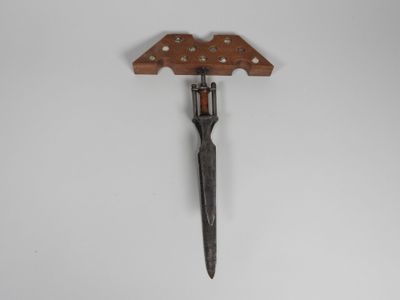 a close up of a knife with a wooden handle on a wall