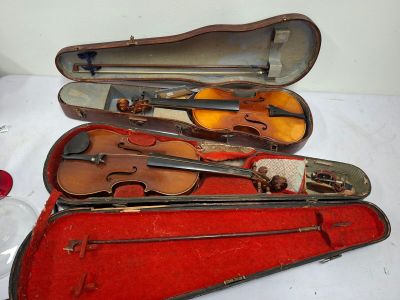 four violins in a red case on a white table