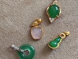 three pieces of green and pink jewelry on a beige carpet