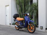 a blue and orange scooter parked in front of a building
