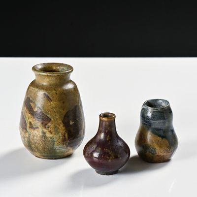trois vases posés sur une table blanche, sur fond noir