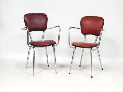 pair of red chairs with chrome legs and armrests against a white wall