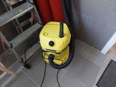a yellow vacuum sitting on the floor next to a red wall
