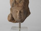 une tête de femme antique posée sur un socle transparent