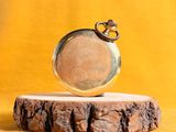 a gold pocket watch sitting on top of a piece of wood