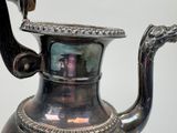 a silver tea pot with a handle on a table