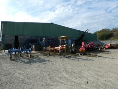 beaucoup de matériel agricole devant un bâtiment vert