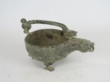an old bronze bowl with a handle on a white surface